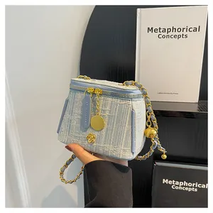 Detail of tweed vanity bag with gold camellia clasp and chain strap