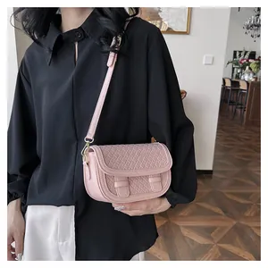 Detail of pink saddle bag with quilted texture and golden hardware shown on a model