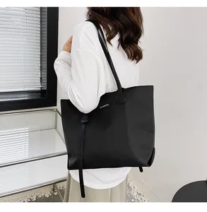 Detailed side view of a large black waterproof nylon tote bag worn by a model