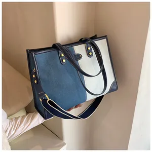 Close-up of contrast denim patchwork tote bag with gold rivets and leather handles