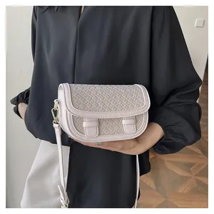 Detail of light beige saddle bag with woven texture and gold metal hardware