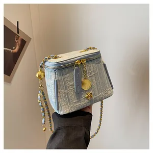 Detail of light blue tweed box bag with gold camellia charm and chain strap