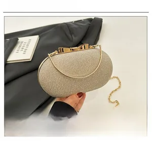 Detail of champagne gold evening clutch with metal bow clasp and detachable chain strap