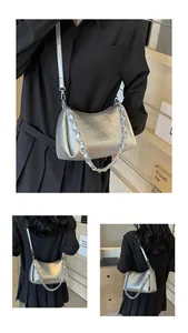 Detail of silver crescent bag with ruched texture and chunky metal chain strap