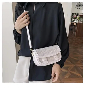 Detailed view of cream saddle bag with woven pattern and gold metal hardware
