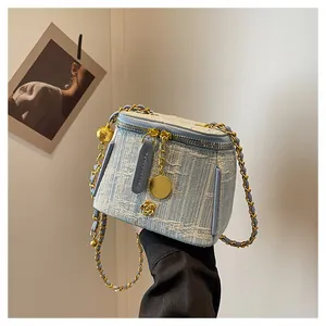 Detailed view of light blue tweed vanity bag with gold chain and camellia charm