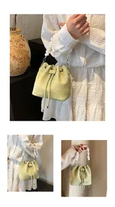 Detail of pistachio green drawstring bucket bag with large white bead handle and silver metal