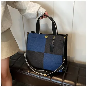 Détail du sac cabas en denim avec fermoir tournant doré et bandoulière tissée amovible