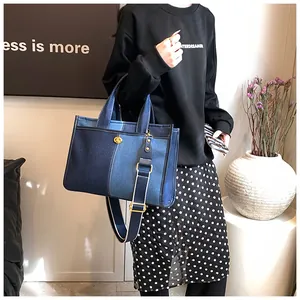 Détail du sac cabas en denim bicolore avec fermoir tournant doré et bandoulière