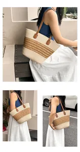 Detail of beige straw tote bag with brown stripes and leather handles in a summer setting