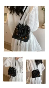 Detail of black drawstring bucket bag with decorative brown translucent beaded handle