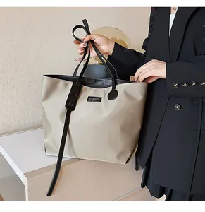 Detail of waterproof nylon tote with leather handles and metallic brand logo plate
