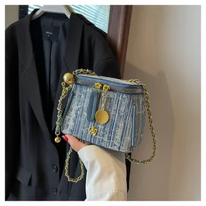 Detailed texture of denim striped bucket bag with gold chain and flower charm