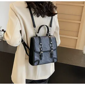 Detail of vintage gray textured backpack with black leather trim and metal buckles
