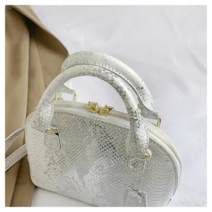 Close-up of white python textured shell bag with gold hardware and top handle