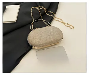 Detail showing gold glitter evening clutch bag size compared to a smartphone