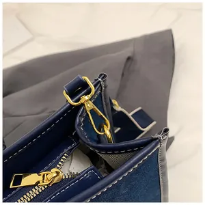 Detail of navy canvas tote bag featuring contrast white stitching and gold hardware accents