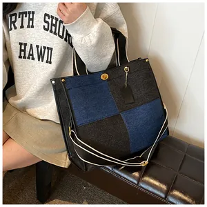 Détail du sac cabas en denim bicolore avec fermoir rotatif en métal doré et pendentif
