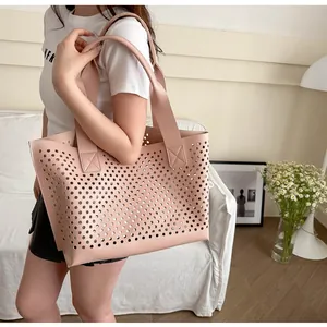 Pink laser-cut tote bag with circular hollow pattern shown being carried by a model