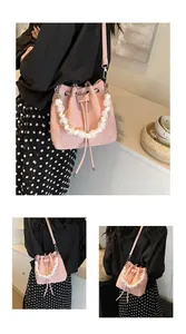 Detail of pink bucket bag with drawstring closure and decorative pearl handle