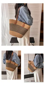 Detail of woven straw tote bag with black stripes and brown leather straps for summer