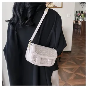 Detail of cream saddle bag with woven diamond pattern and gold hardware on model