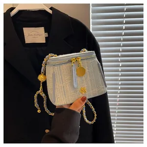 Detail of light blue tweed bucket bag with gold flower logo and metal chain strap