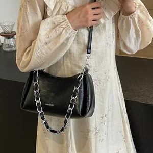 Chic black leather underarm bag with silver chain strap shown on a floral dress