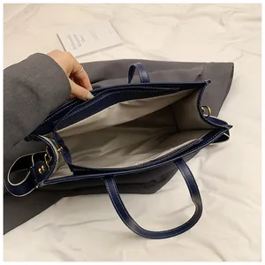 Detail view of large navy tote bag featuring light gray lining and secure zipper pocket