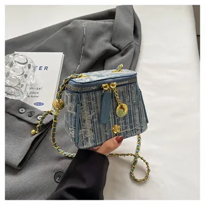 Close-up of blue tweed bucket bag with gold flower detail and chain strap