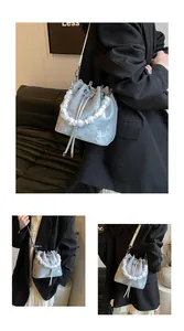 Detail of silver drawstring bucket bag with large faux pearl handle and metal matte finish