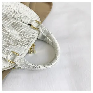 Close-up of white snake pattern texture and gold metal hardware on luxury handbag