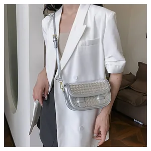 Detail of silver woven saddle bag showing metallic texture on white blazer outfit