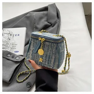 Detail view of mini bucket bag in blue tweed with gold chain and floral charm