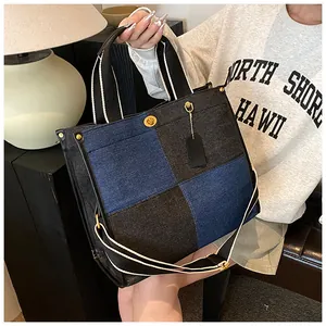 Détails du grand sac cabas en denim avec coutures contrastées et fermoir rotatif doré