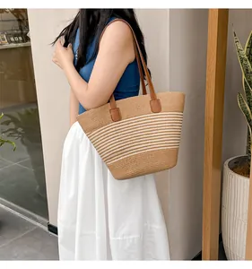 Detail of hand-woven straw tote bag with striped pattern and brown leather straps