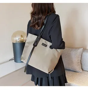 Detailed back view of a beige nylon tote bag with black straps worn by a model