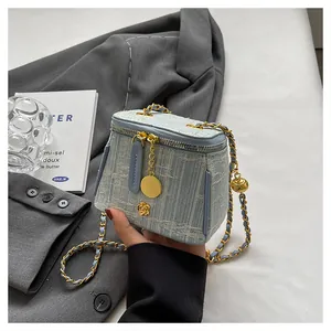Close-up of light blue tweed bucket bag featuring golden chain and camellia metal ornament