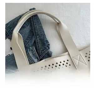 Detail of wide reinforced faux leather handles on a cream laser-cut tote bag