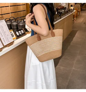 Close-up of handwoven straw tote with white stripes and brown leather shoulder straps