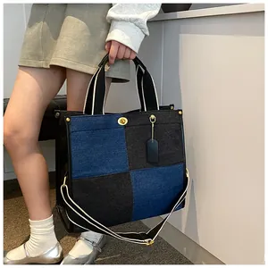 Détails du sac cabas en denim bicolore avec fermoir rotatif doré et finitions en cuir noir