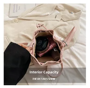 Pink drawstring bucket bag internal capacity with pearl handle showing phone and makeup