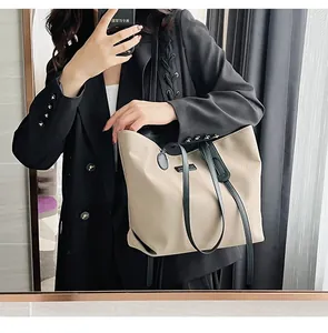 Mirror selfie showing a spacious beige nylon tote bag with black straps and suit styling