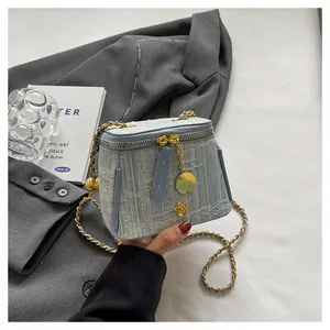Detail of light blue tweed crossbody bag with golden chain and floral charm pendant