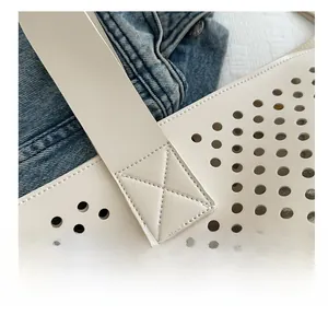 Close-up of laser-cut perforated faux leather tote bag with reinforced shoulder strap stitching