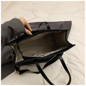 Detail view of large black leather tote bag with functional interior compartments