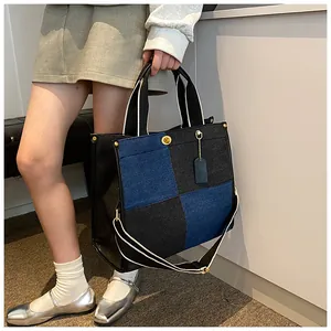 Détail du sac cabas patchwork en denim bleu et noir avec rivets dorés et étiquette
