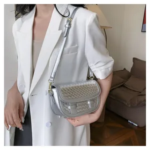 Silver saddle bag with woven texture and adjustable strap shown on a model