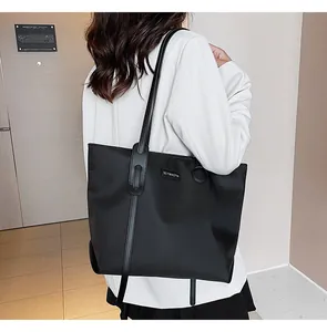 Detail of waterproof black nylon tote bag with leather straps and metal brand logo