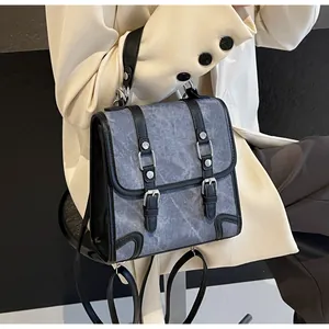 Detail of vintage grey denim backpack featuring black leather straps and silver metal buckles